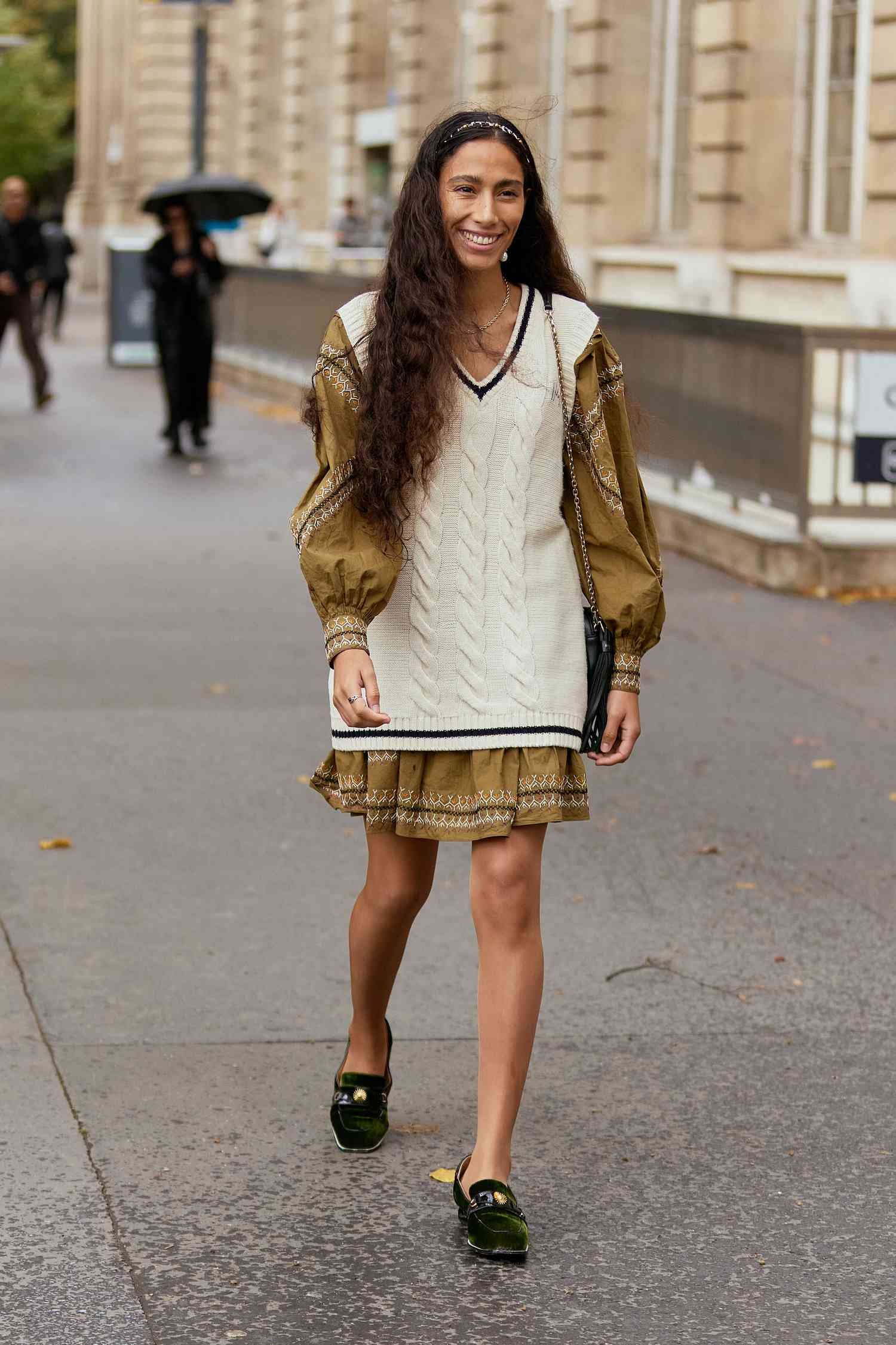 Person wear brown dress with pick ribbed sweater and black loafers