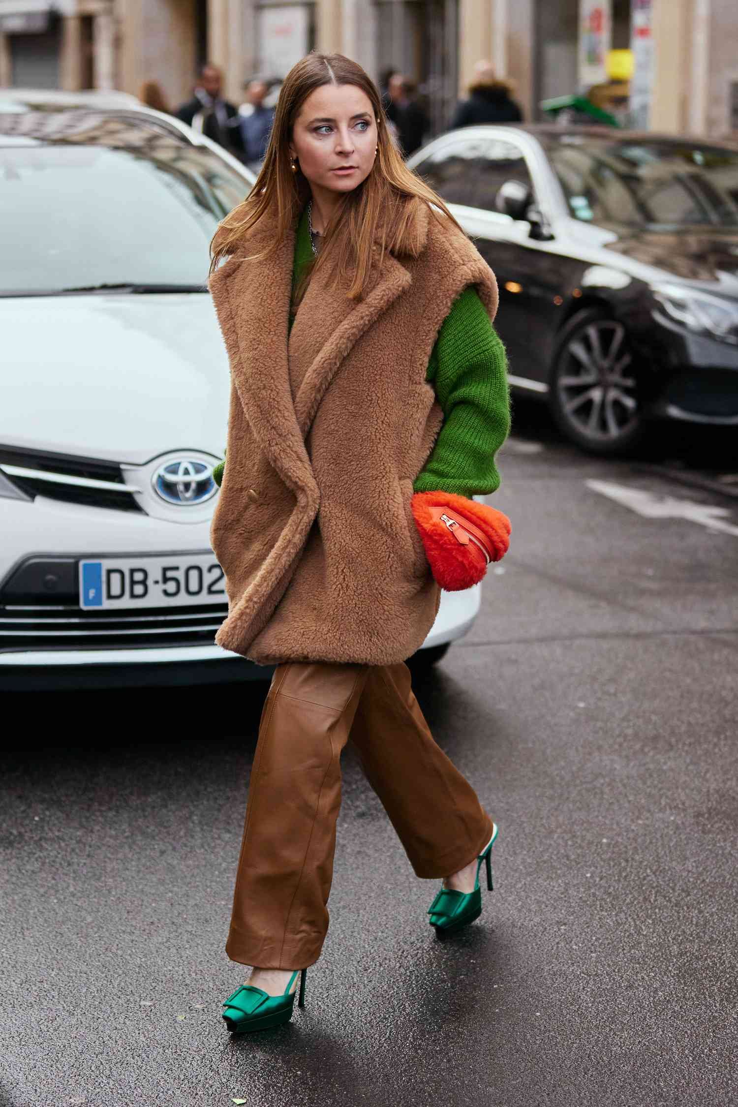 Person wears fuzzed brown vest, viridity sweater, brown trouser, and green pumps