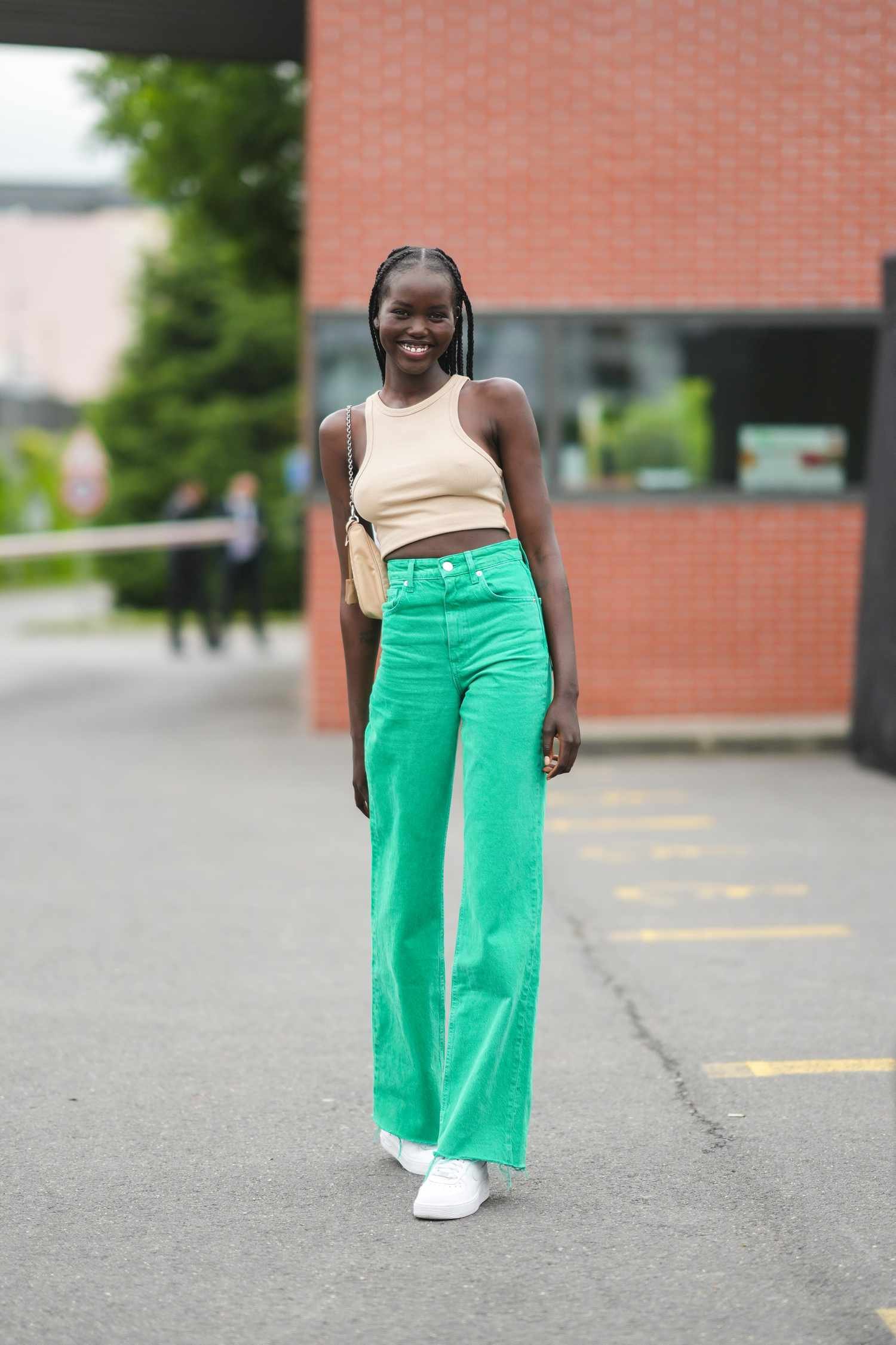 Person wears green colored denim jeans with a neutral crop top