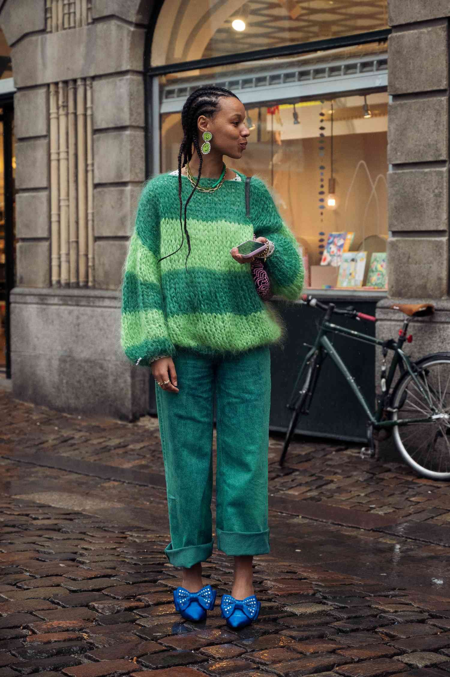 A adult female wear greenness colored jean and blue bow shoes.