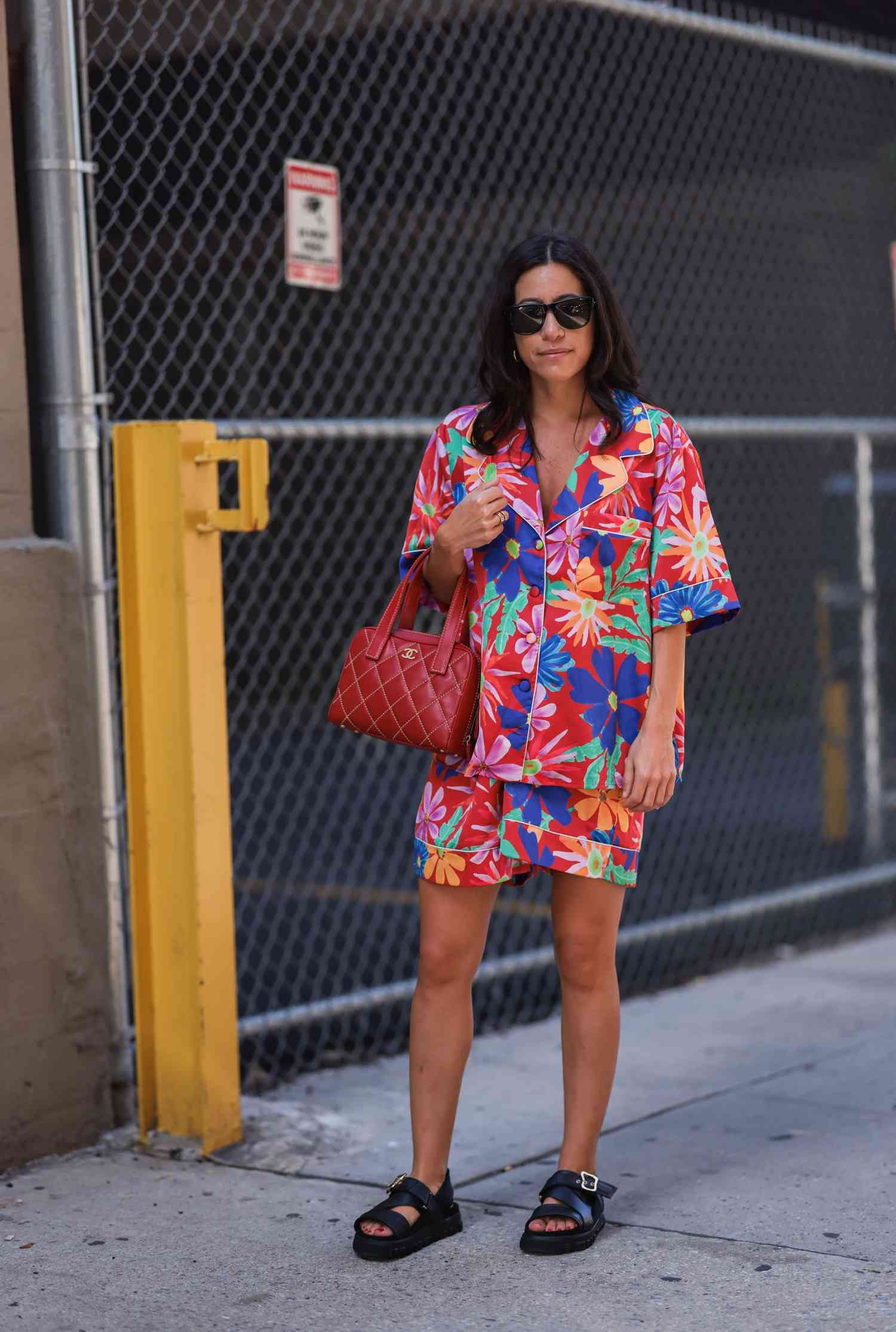 Woman eating away A red Chanel bag, flower printed outfit set, chunky black sandals, and black sunglasses