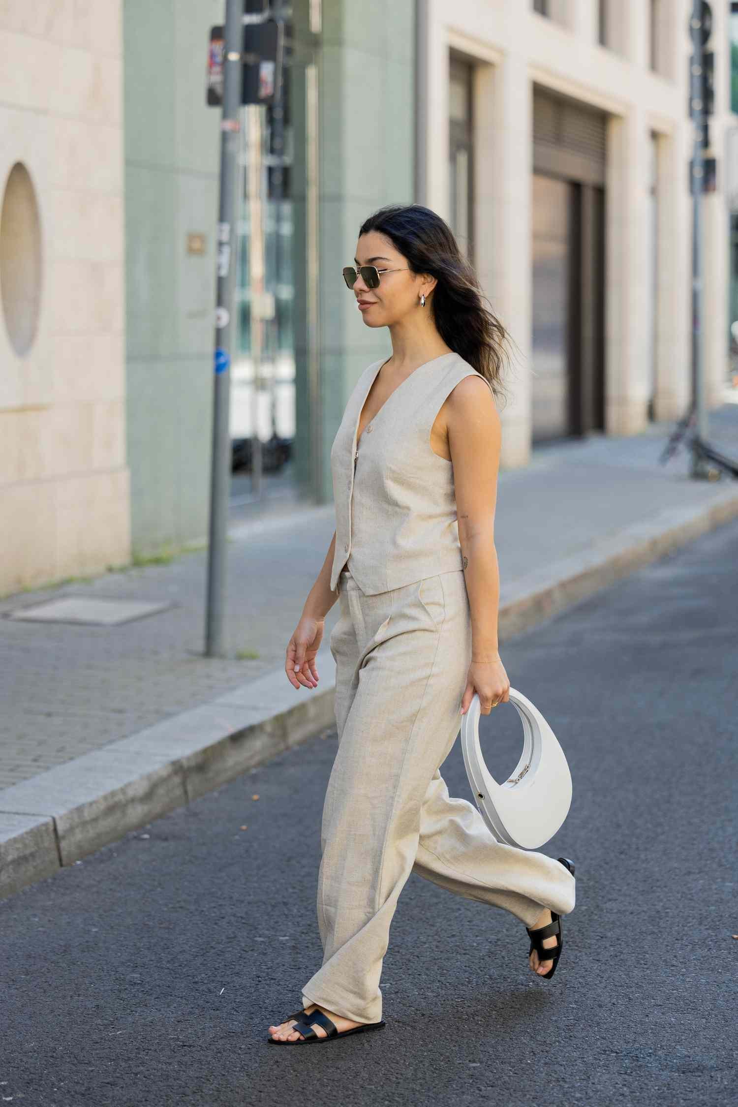 A woman wears a waistcoat and sandals