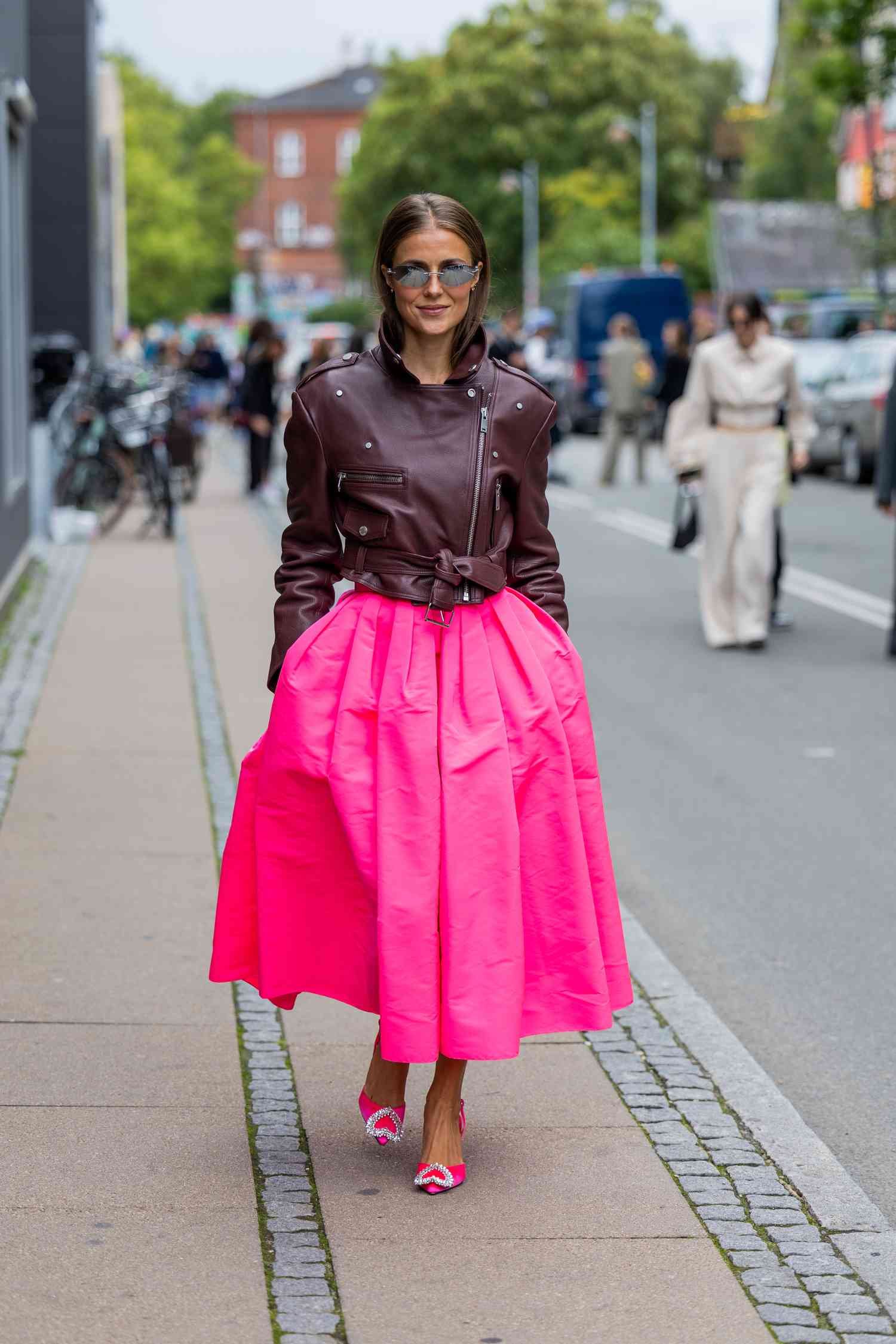 Person wearing angstrom unit brown Burgundy leather jacket with a voluminous neon pink skirt