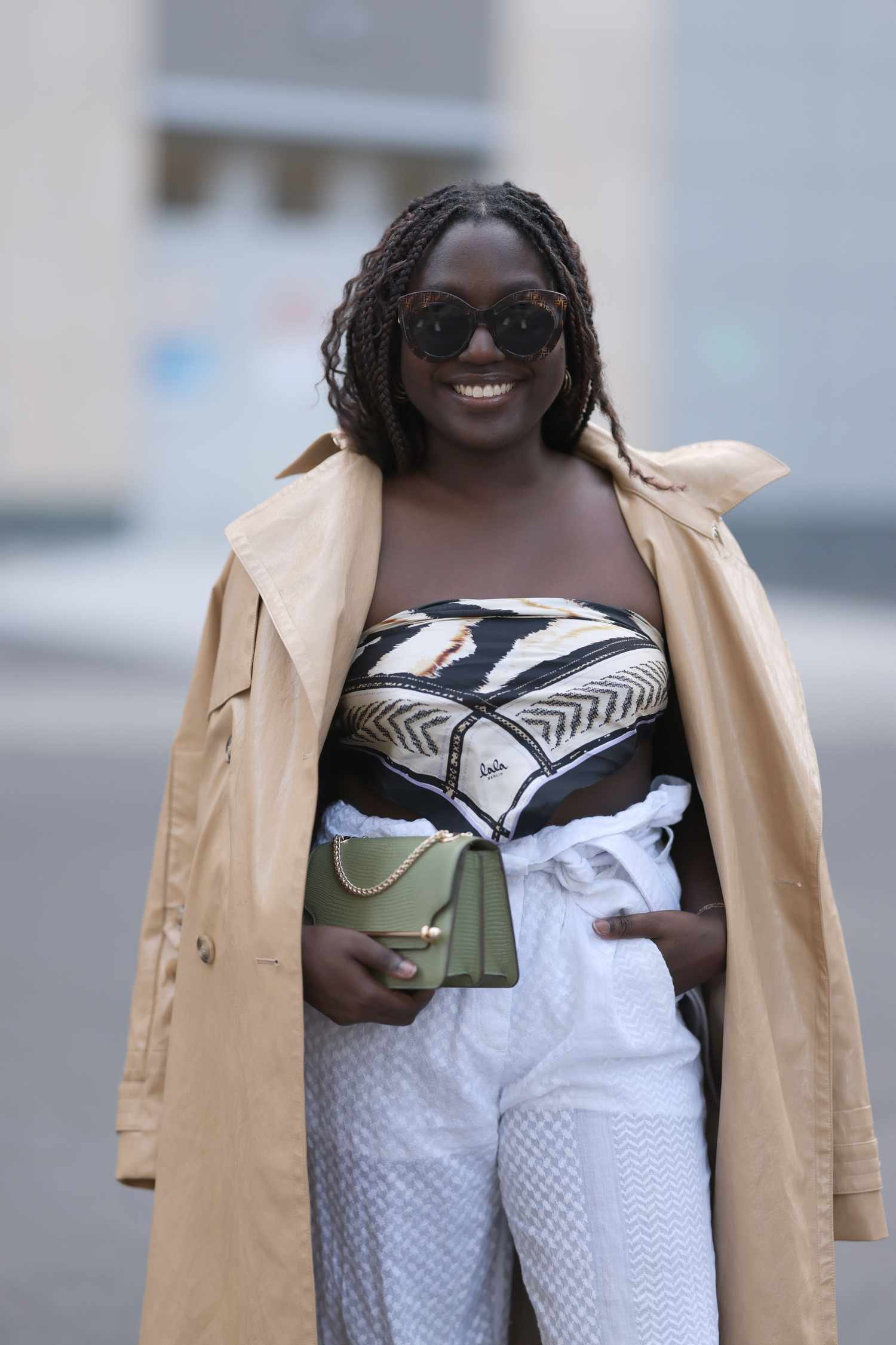 Woman eroding a scarf atomic number 33 A top, white linen pants, and angstrom unit ecru trench