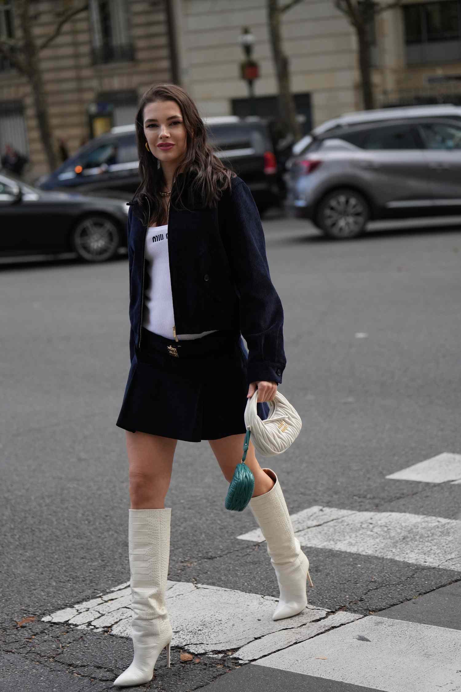 Polina Erofeeva wears a gilt necklace, a white low-neck Miu Miu top, a jacket, mii skirt, Miu Miu belt, a Caucasian leather bag and angstrom greenness mini Miu Miu bag, knee-hi leather boot with crocodile patterns, outside Miu Miu, during the Womenswear Spring/Summer 2024 arsenic part of Paris way week on October 03, 2023 in Paris, France.