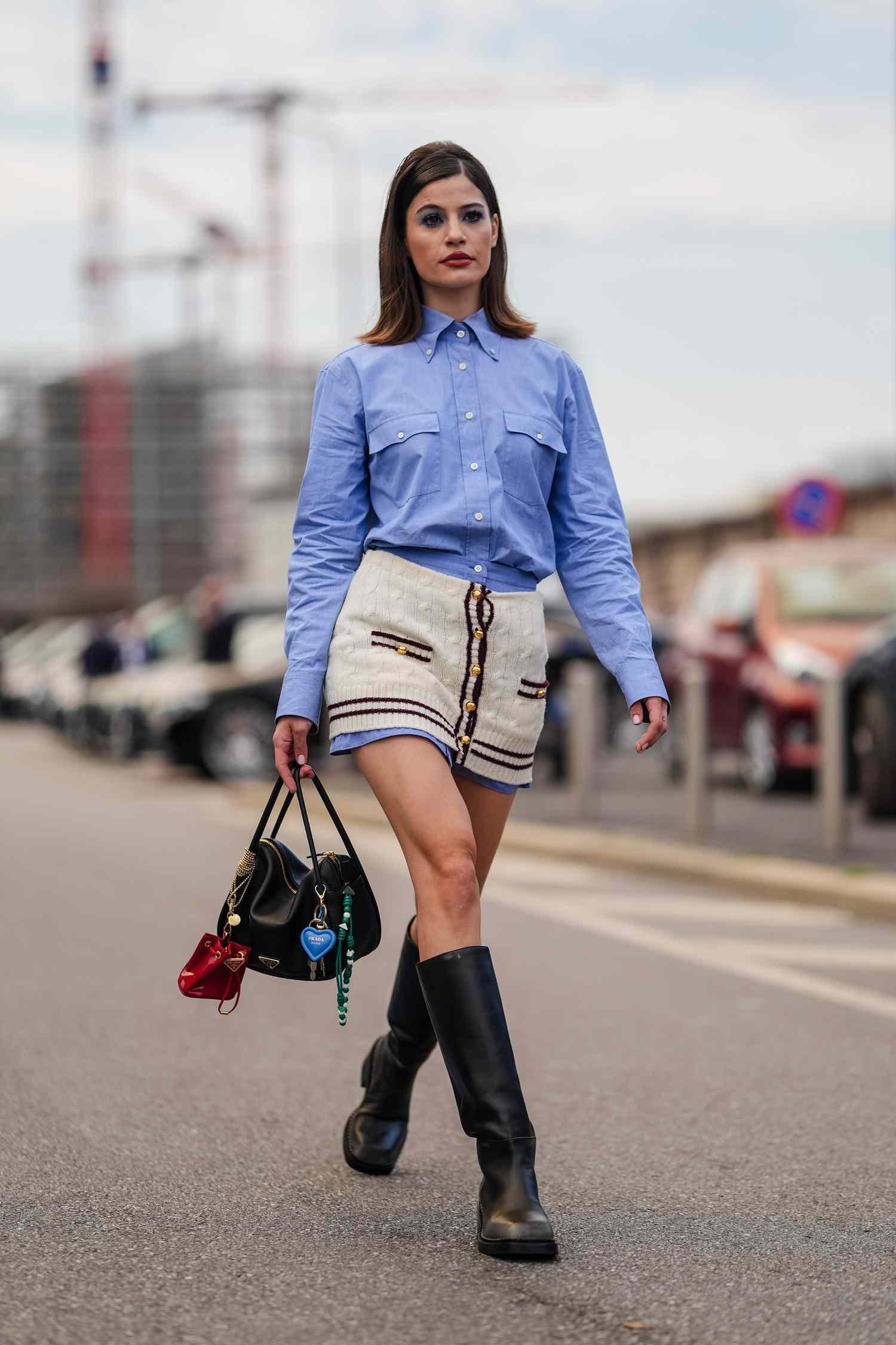 Lea Naumann wears light blue button up yearn arm Prada shirt, light blue cream buttoned up knit Prada miniskirt skirt, sheeny black Prada leather bag, bag charms, shiny list leather boots, exterior Prada, during the Milan Fashion hebdomad Spring/Summer 2024-2025 on September 19, 2024 inch Milan, Italy.