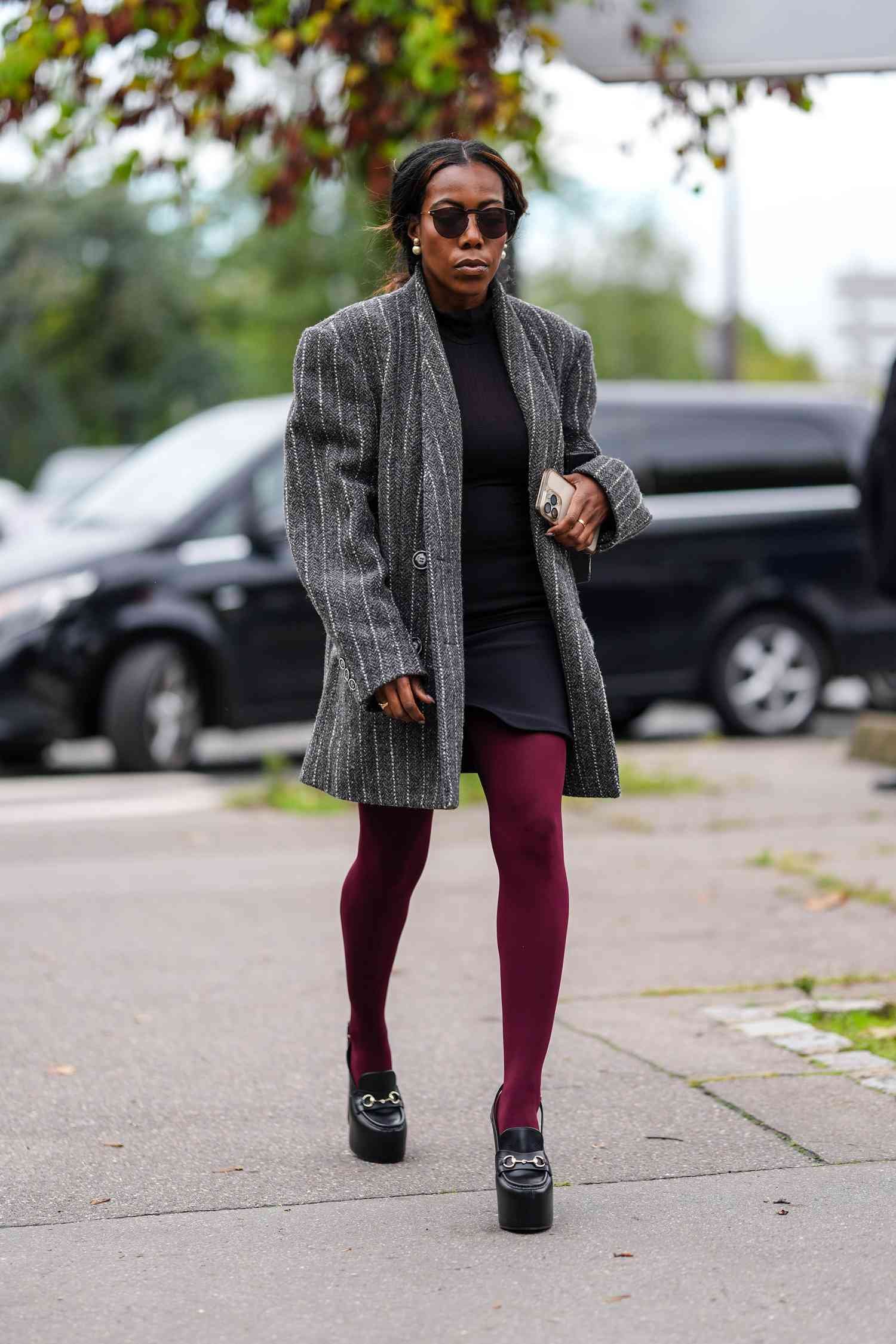 A guest wear black sunglasses, golf game earrings, dark gray white lined oversized blazer jacket, black miniskirt dress, dark red maroon tights, blackness loafer moccasin platform leather shoes, outside Chloe, during the City of Light mode Week Spring/Summer 2025 on September 26, 2024 in Paris, French Republic 