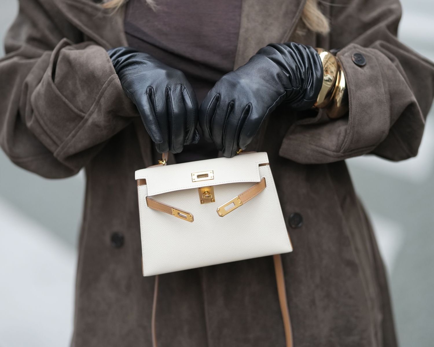 a individual wearing black leather glove and transport a cream hermes Kelly bag